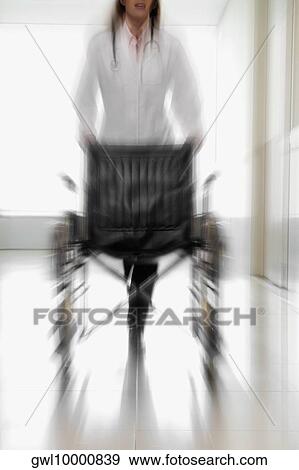 Female doctor pushing an empty wheelchair View Large Photo Image Stock Photo - Female doctor pushing an empty wheelchair. Fotosearch