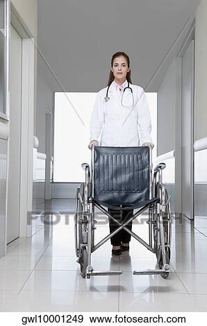 Female doctor pushing an empty wheelchair View Large Photo Image Stock Photo - Female doctor pushing an empty wheelchair. Fotosearch