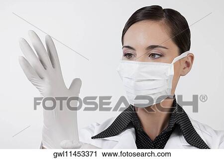 Female doctor putting on surgical gloves View Large Photo Image Stock Image - Female doctor putting on surgical gloves. Fotosearch