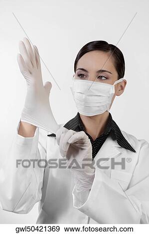 Female doctor putting on surgical gloves View Large Photo Image Stock Photo - Female doctor putting on surgical gloves. Fotosearch