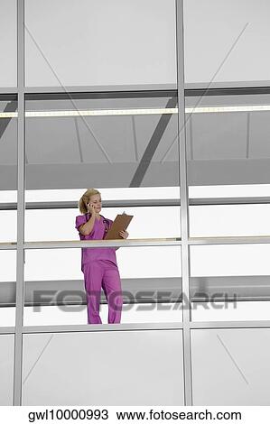 Female doctor talking on a mobile phone in a hospital View Large Photo Image Stock Image - Female doctor talking on a mobile phone in a hospital. Fotosearch