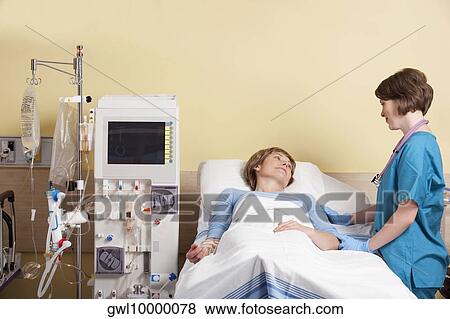 Stock Photo - Female doctor talking to a patient lying in a hospital bed. Fotosearch