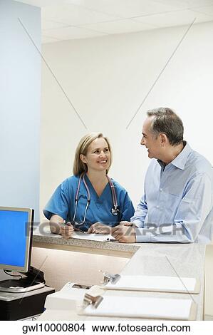 Female doctor talking with a patient at a reception counter in a hospital View Large Photo Image Picture - Female doctor talking with a patient at a reception counter in a hospital. Fotosearch