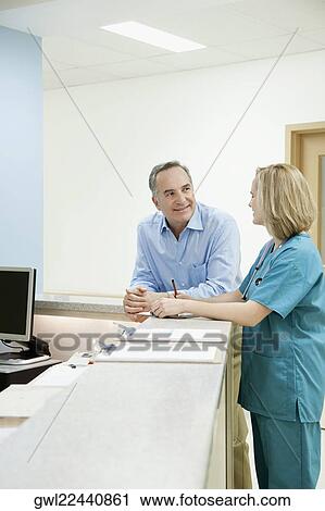 Female doctor talking with a patient at a reception counter in a hospital View Large Photo Image Stock Image - Female doctor talking with a patient at a reception counter in a hospital. Fotosearch