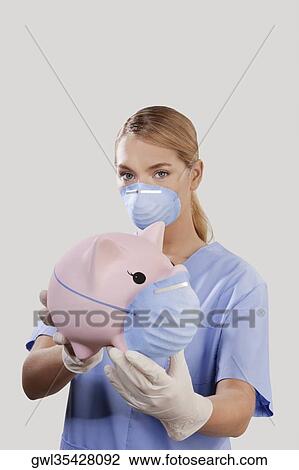 Female doctor wearing a flue mask and showing a piggy bank View Large Photo Image Stock Image - Female doctor wearing a flue mask and showing a piggy bank. Fotosearch