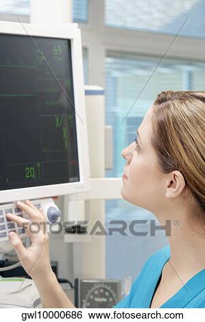 Female doctor working on a cardiac monitor View Large Photo Image Stock Photograph - Female doctor working on a cardiac monitor. Fotosearch
