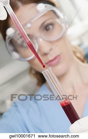 Stock Image - Female lab technician analyzing a blood sample in a test tube. Fotosearch
