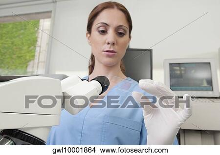 Picture - Female lab technician analyzing a sample in a laboratory. Fotosearch