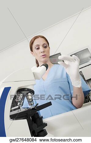 Picture - Female lab technician analyzing a sample in a laboratory. Fotosearch