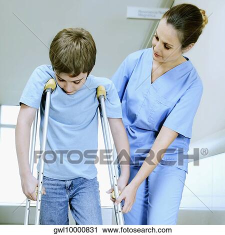 Female nurse assisting a boy on crutches View Large Photo Image Stock Image - Female nurse assisting a boy on crutches. Fotosearch
