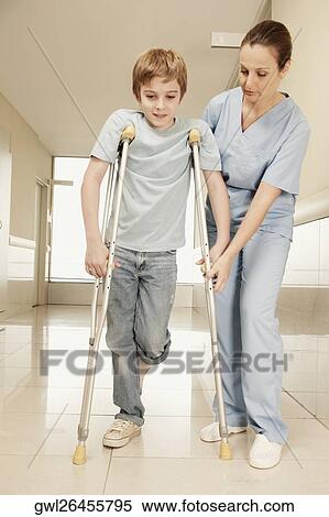 Female nurse assisting a boy on crutches View Large Photo Image Stock Photography - Female nurse assisting a boy on crutches. Fotosearch