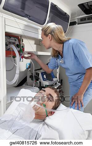 Female nurse assisting a patient in an ambulance View Large Photo Image Stock Photograph - Female nurse assisting a patient in an ambulance. Fotosearch