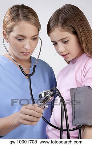 Female nurse checking the blood pressure of a girl View Large Photo Image Stock Photo - Female nurse checking the blood pressure of a girl. Fotosearch