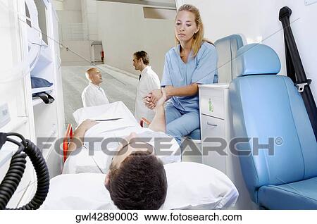 Female nurse consoling a patient lying on gurney View Large Photo Image Stock Image - Female nurse consoling a patient lying on gurney. Fotosearch