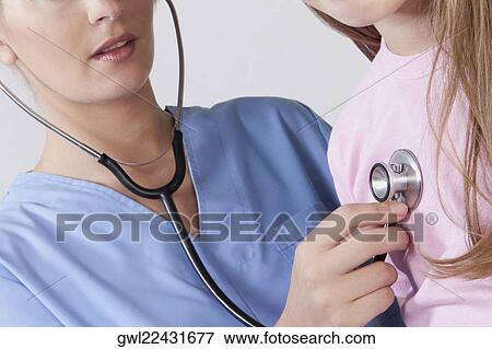 Female nurse examining a girl with a stethoscope View Large Photo Image Stock Photo - Female nurse examining a girl with a stethoscope. Fotosearch