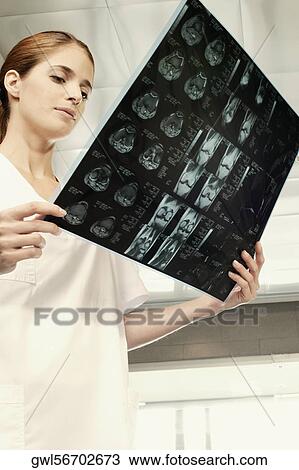 Stock Image - Female nurse examining an X-Ray. Fotosearch