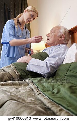 Female nurse giving medicine to a man View Large Photo Image Stock Image - Female nurse giving medicine to a man. Fotosearch