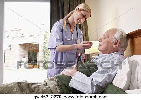 Female nurse giving medicine to a man View Large Photo Image Stock Photo - Female nurse giving medicine to a man. Fotosearch