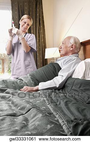 Female nurse holding a syringe and standing near a patient View Large Photo Image Stock Image - Female nurse holding a syringe and standing near a patient. Fotosearch
