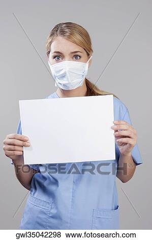 Female nurse wearing a flu mask and holding blank placard View Large Photo Image Stock Photo - Female nurse wearing a flu mask and holding blank placard. Fotosearch