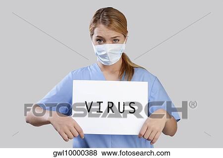 Stock Photo - Female nurse wearing a flu mask holding placard with word VIRUS written on it. Fotosearch