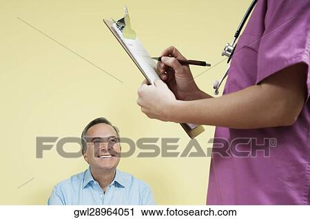 Female nurse writing a prescription with a patient looking at her View Large Photo Image Stock Image - Female nurse writing a prescription with a patient looking at her. Fotosearch