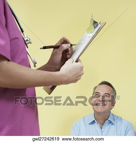 Female nurse writing a prescription with a patient looking at her View Large Photo Image Stock Photo - Female nurse writing a prescription with a patient looking at her. Fotosearch