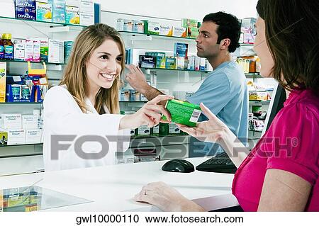 Stock Image - Female pharmacist giving medicine to a customer. Fotosearch