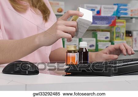 Stock Photography - Female pharmacist holding a medicine in a pharmacy. Fotosearch