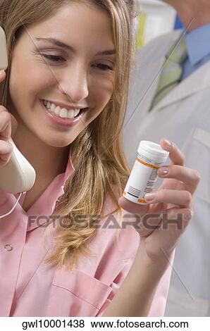Female pharmacist holding a medicine bottle and talking on the telephone View Large Photo Image Stock Photo - Female pharmacist holding a medicine bottle and talking on the telephone. Fotosearch