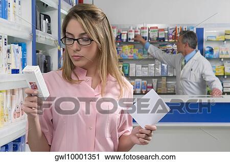 Female pharmacist holding a prescription and looking at a medicine View Large Photo Image Stock Image - Female pharmacist holding a prescription and looking at a medicine. Fotosearch