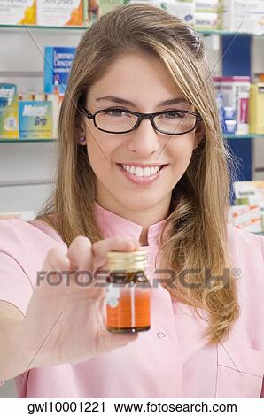 Stock Image - Female pharmacist showing a medicine bottle. Fotosearch