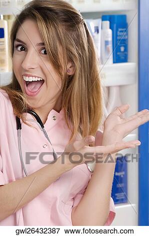 Stock Photo - Female pharmacist showing a welcome gesture in a pharmacy. Fotosearch