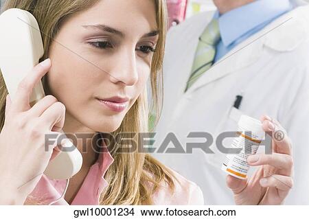 Picture - Female pharmacist talking on the telephone. Fotosearch