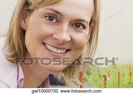 Female scientist smiling near plants in a laboratory View Large Photo Image Stock Image - Female scientist smiling near plants in a laboratory. Fotosearch