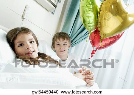 Girl holding balloons on a hospital bed with her brother beside her View Large Photo Image Stock Image - Girl holding balloons on a hospital bed with her brother beside her. Fotosearch