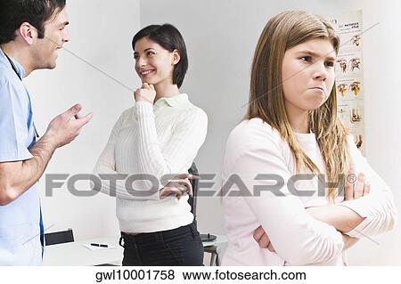 Girl looking upset from her mother and doctor View Large Photo Image Stock Photo - Girl looking upset from her mother and doctor. Fotosearch