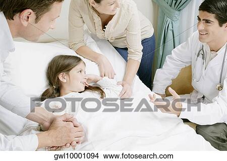 Girl on a hospital bed and her parents discussing with a doctor View Large Photo Image Picture - Girl on a hospital bed and her parents discussing with a doctor. Fotosearch