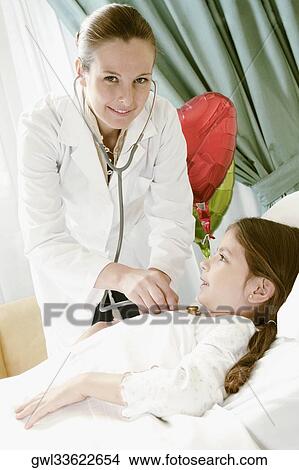 Girl on a hospital bed being examined by a female doctor View Large Photo Image Picture - Girl on a hospital bed being examined by a female doctor. Fotosearch
