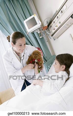Girl on a hospital bed with a female doctor examining a stuffed toy View Large Photo Image Stock Image - Girl on a hospital bed with a female doctor examining a stuffed toy. Fotosearch