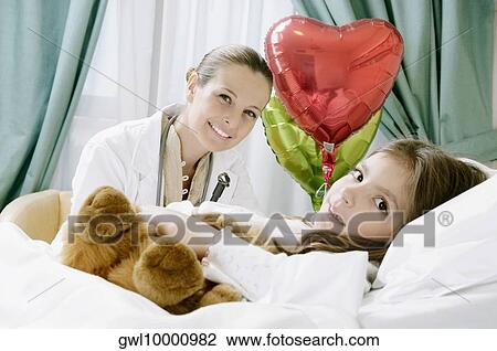 Girl on a hospital bed with a female doctor beside her View Large Photo Image Stock Image - Girl on a hospital bed with a female doctor beside her. Fotosearch