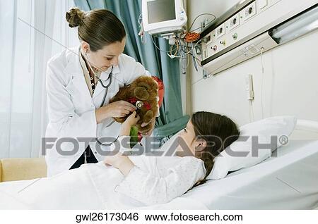 Girl on a hospital bed with a female doctor examining a stuffed toy View Large Photo Image Stock Photograph - Girl on a hospital bed with a female doctor examining a stuffed toy. Fotosearch