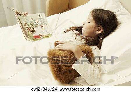Girl reading a comic book on a hospital bed View Large Photo Image Picture - Girl reading a comic book on a hospital bed. Fotosearch