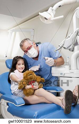 Stock Image - Girl smiling with a dentist standing beside her. Fotosearch