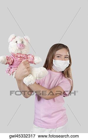 Girl wearing flu mask and holding a stuffed toy View Large Photo Image Stock Photo - Girl wearing flu mask and holding a stuffed toy. Fotosearch