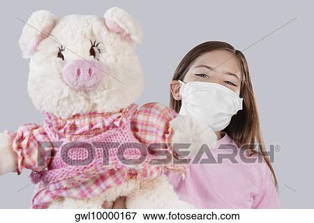 Stock Photo - Girl wearing flu mask and showing a stuffed toy. Fotosearch