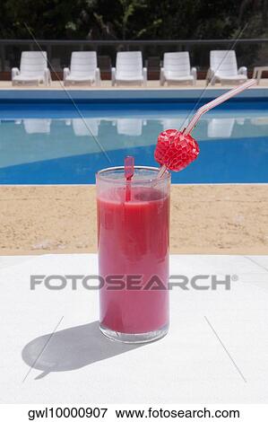 Stock Photo - Glass of fruit juice at the poolside. Fotosearch