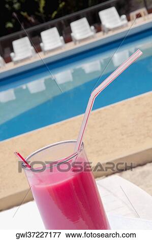 Stock Photo - Glass of fruit juice at the poolside. Fotosearch