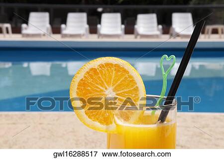 Stock Photo - Glass of orange juice at the poolside. Fotosearch