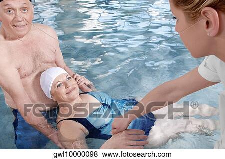 Health worker and a man assisting a woman in a swimming pool View Large Photo Image Stock Photo - Health worker and a man assisting a woman in a swimming pool. Fotosearch